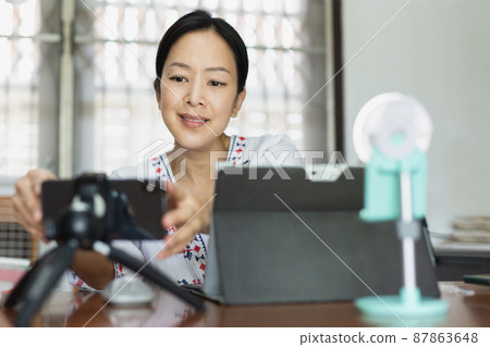 Woman working online preparing broadcasting live in home office. Woman working online preparing broadcasting live in home office. 87863648