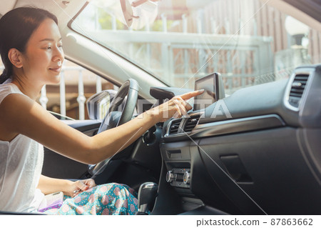 Woman driving car with hand touching navigation on monitor screen. 87863662