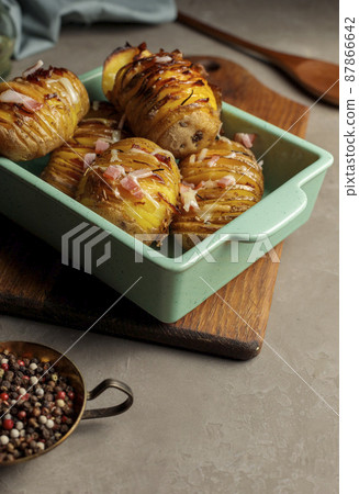 Baked potatoes with spices and cheese. In a blue ceramic mold. Vertical frame, close-up. Baked potatoes with spices and cheese. In a blue ceramic mold. Vertical frame, close-up. 87866642