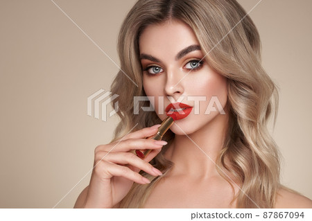 A beautiful young blonde woman applying lipstick A beautiful young blonde woman applying lipstick 87867094