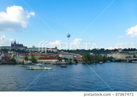 View of the Vltava river and a hot air balloon flying over the city of Prague, Czech Republic 87867471