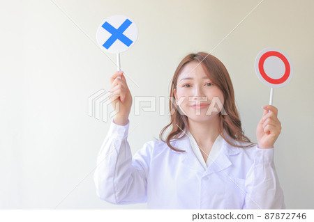 A smiling white coat woman with a plate of 〇 and X 1 A smiling white coat woman with a plate of 〇 and X 1 87872746