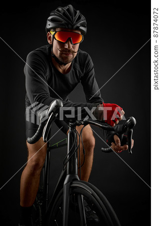 male cyclist riding road bicycle on black background male cyclist riding road bicycle on black background 87874072