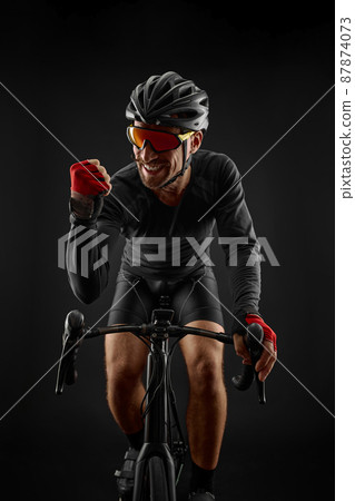 male cyclist riding road bicycle on black background male cyclist riding road bicycle on black background 87874073