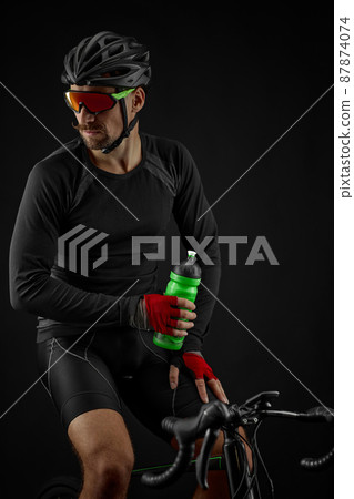 male cyclist riding road bicycle on black background male cyclist riding road bicycle on black background 87874074
