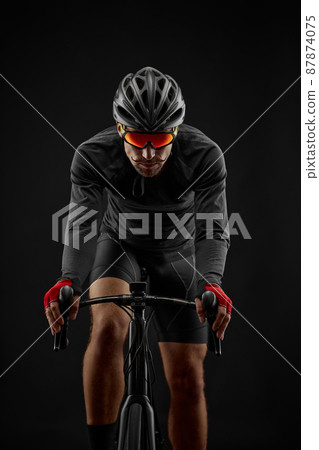 male cyclist riding road bicycle on black background male cyclist riding road bicycle on black background 87874075