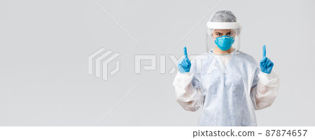 Covid-19, preventing virus, health, healthcare workers and quarantine concept. Determined young doctor or nurse working with patients sick coronavirus, pointing fingers up, wear protective suit Covid-19, preventing virus, health, healthcare workers and quarantine concept. Determined young doctor or nurse working with patients sick coronavirus, pointing fingers up, wear protective suit 87874657