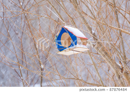 Wooden hand made big birdhouse. Bird and small animal feeder in winter forest. Wooden hand made big birdhouse. Bird and small animal feeder in winter forest. 87876484