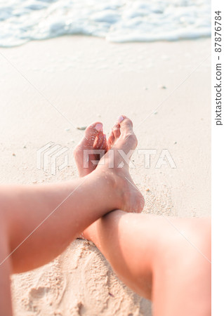 Woman's feet on the white sand beach in shallow water Woman's feet on the white sand beach in shallow water 87876784