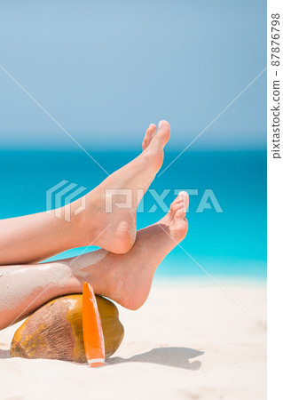 Woman's feet on the white sand beach in shallow water Woman's feet on the white sand beach in shallow water 87876798