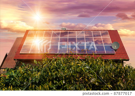 Photo collage of solar panels, photovoltaics on the red roof of a house and a beautiful sky with the setting sun. Alternative electricity source. Concept of sustainable resources 87877017