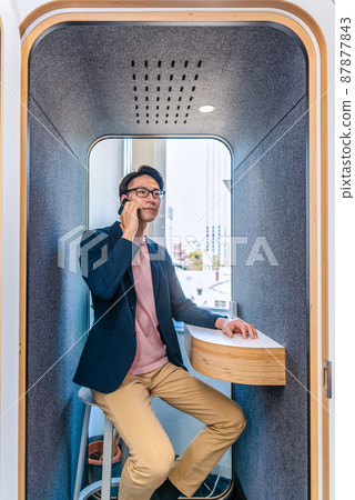 A man calling in a soundproof telephone booth in a free address office A man calling in a soundproof telephone booth in a free address office 87877843