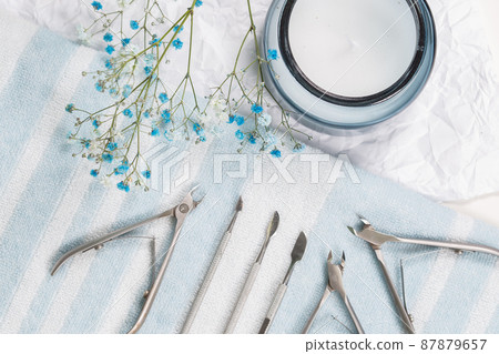 Manicure tools are laid out on a white-blue striped towel, studio photo Manicure tools are laid out on a white-blue striped towel, studio photo 87879657