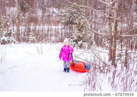 Little girl drags slide-slide cheesecake up snowy hill. 87879916