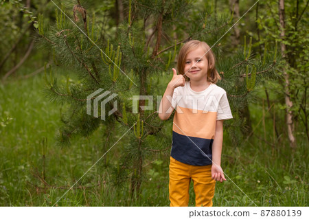 Blond charming caucasian girl in casual closing showing thumb up in the forest Blond charming caucasian girl in casual closing showing thumb up in the forest 87880139