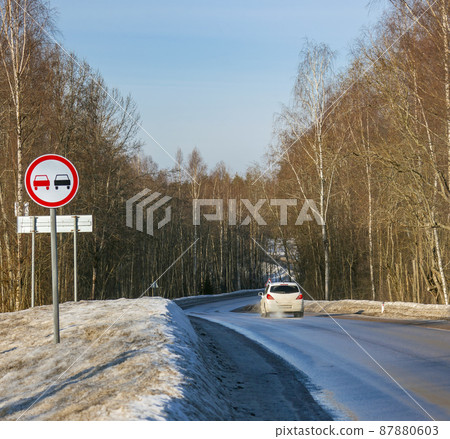 Dangerous turn with car on country road among trees. 87880603