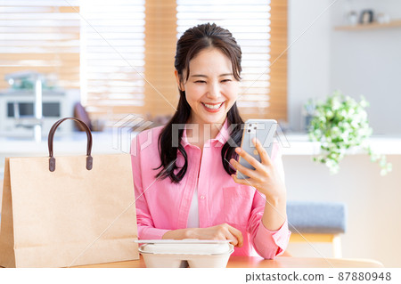 年輕女子在她的智能手機上訂購 87880948