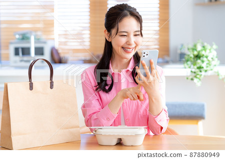 年輕女子在她的智能手機上訂購 87880949