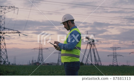 technology concept with high voltage power lines. electrical engineer helmet digital tablet sunset. power engineer power plant high voltage voltage energy. concept electrical engineer working sunset 87881313