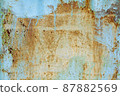 Brown beige abstract background with orange blue hues. A rust-eaten textured sheet of metal with remnants of paint marks. 87882569