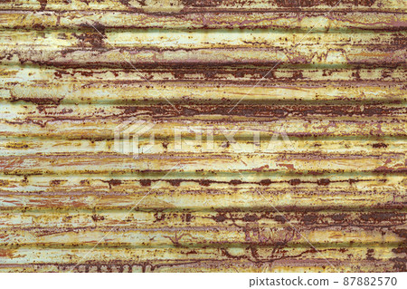 Red brown abstract background with pink and beige shades. A rust-eaten ribbed textured sheet of metal with remnants of paint marks. Red brown abstract background with pink and beige shades. A rust-eaten ribbed textured sheet of metal with remnants of paint marks. 87882570