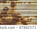 Silver abstract background with pink red brown shades. A rust-eaten ribbed textured sheet of metal with remnants of paint marks. 87882571