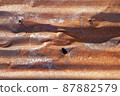 Brown abstract background with silver red hues. A weathered, rust-eaten, crumpled, perforated textured sheet of metal. 87882579