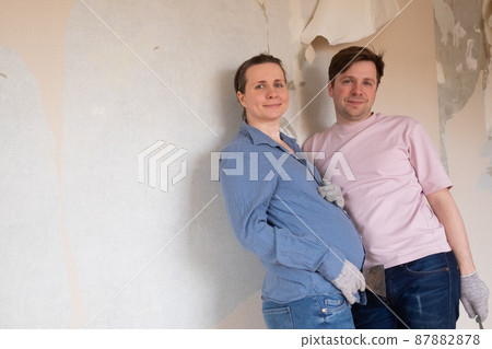 Young couple removing old wallpaper from walls preparing for flat renovation. 87882878