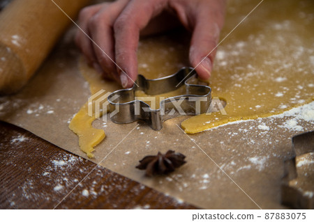 Cookies are cut out of the rolled dough in the form of a man, the pastry chef's hand holds a cookie cutter. High quality photo 87883075
