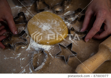 The rolled dough in the form of a circle lies on baking parchment surrounded by cookie cutters. High quality photo 87883077