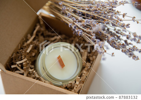 An open box with candles stands on a white background, a dried bouquet of lavender lies on it, close-up photo. High quality photo An open box with candles stands on a white background, a dried bouquet of lavender lies on it, close-up photo. High quality photo 87883132