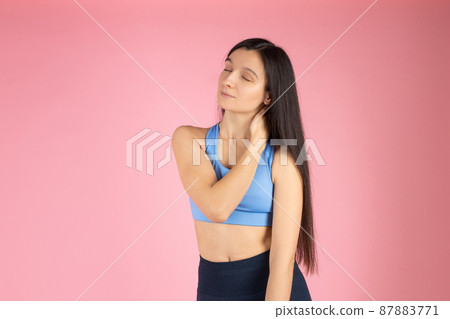 Happy sportswoman smiling, rubbing her neck. Fitness woman workout for healthy body, doing active exercises. Athletic girl feeling pain in her neck on pink background 87883771
