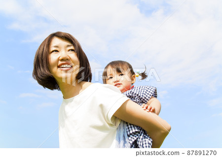 在藍天的背景下，一位母親帶著她的小女兒的特寫鏡頭。母子形象、母性、感情、育兒 87891270