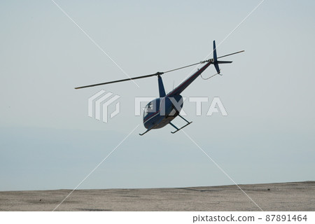 Blue helicopter flying in grey cloudy skies 87891464