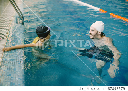 Girl learning to swim with coach at the leisure center Girl learning to swim with coach at the leisure center 87892279