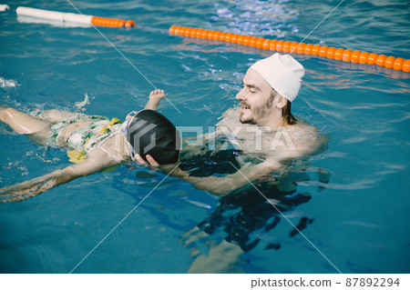 Girl learning to swim with coach at the leisure center Girl learning to swim with coach at the leisure center 87892294