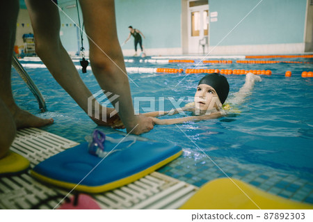 Girl learning to swim with coach at the leisure center Girl learning to swim with coach at the leisure center 87892303