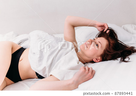 Portrait of a young beautiful brunette lying in bed wearing underwear Portrait of a young beautiful brunette lying in bed wearing underwear 87893441