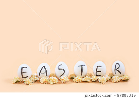 White eggs with black letters EASTER around flowers on yellow background. White eggs with black letters EASTER around flowers on yellow background. 87895319