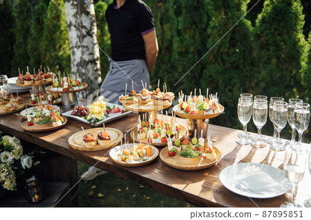 A table of various snacks, sandwiches, strawberries and other types of snacks. 87895851