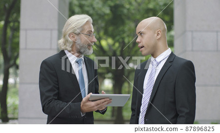 caucasian and latino corporate executives discussing business using digital tablet 87896825