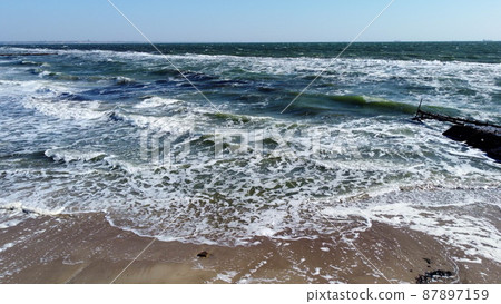 Aerial drone view flight over waves that roll onto the sandy shore. Top view 87897159