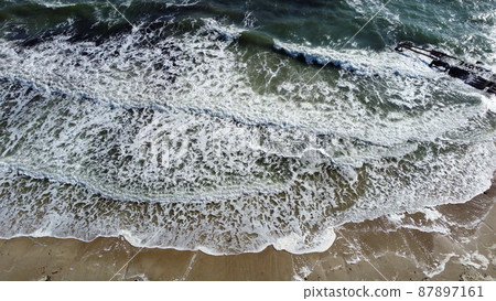 Aerial drone view flight over waves that roll onto the sandy shore. Top view 87897161