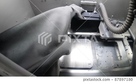 Male worker in rubber glove cleans printing platform inside 3d printer for metal 87897180