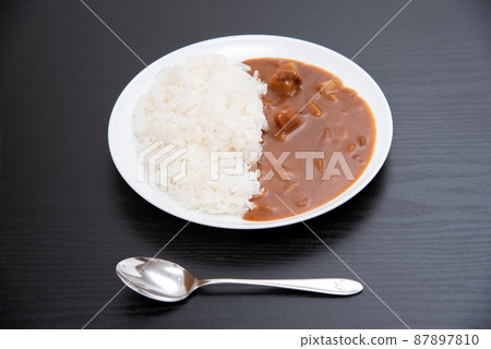 Curry rice served on a round plate on a black background Curry rice served on a round plate on a black background 87897810
