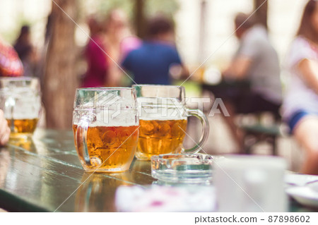 outdoor garden restaurant, in foreground beer in glasses on table outdoor garden restaurant, in foreground beer in glasses on table 87898602