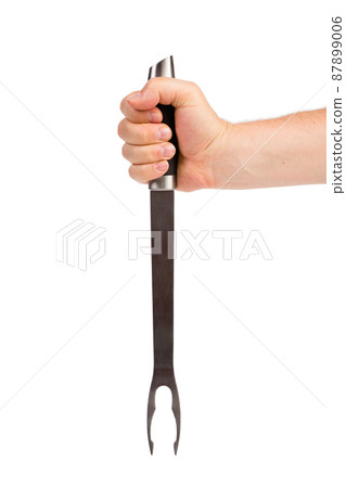 A hand holds a barbecue fork. A hand holds a barbecue fork. 87899006
