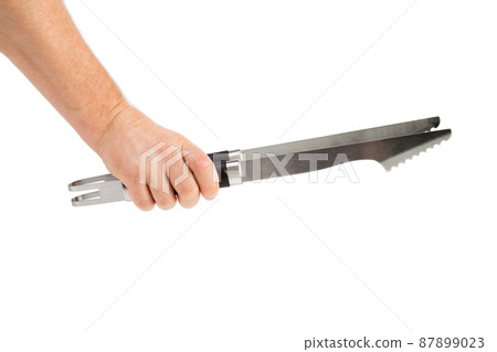 A hand holds a kitchen tong. A hand holds a kitchen tong. 87899023