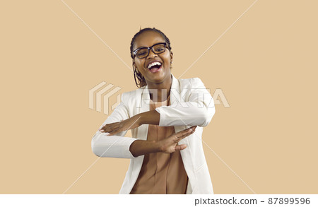Overjoyed young African American woman isolated on pink studio background dancing and laughing. Happy millennial black girl in glasses have fun make dancer moves, celebrate success. 87899596