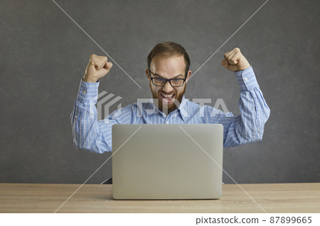 Yes, I did it. Happy euphoric ecstatic businessman in shirt and glasses sitting at table with laptop computer, celebrating success, fist pumping and shouting Hurray. Successful online business concept 87899665
